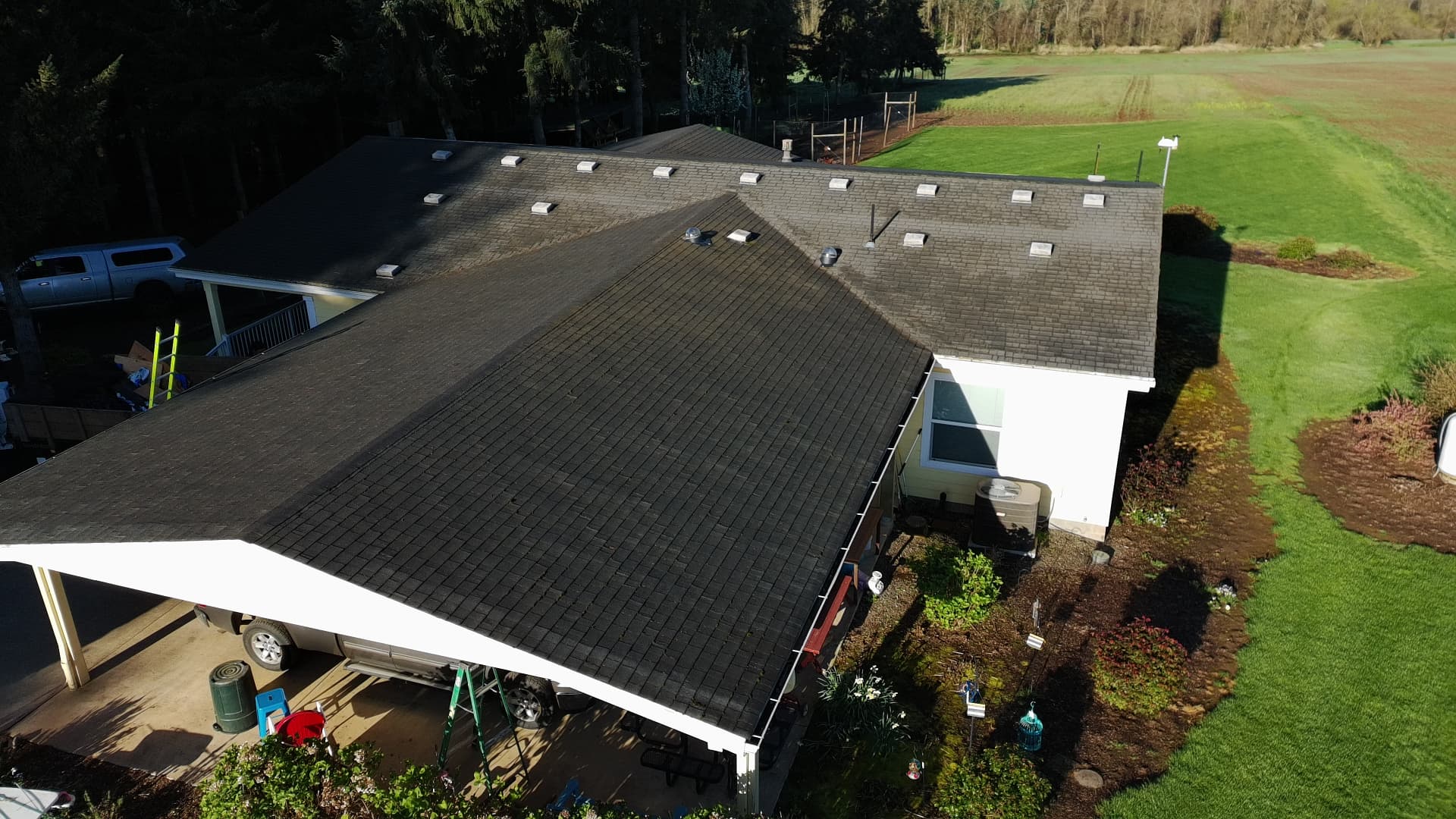 Aerial view of an aging, moss-darkened shingle roof on a country home before service