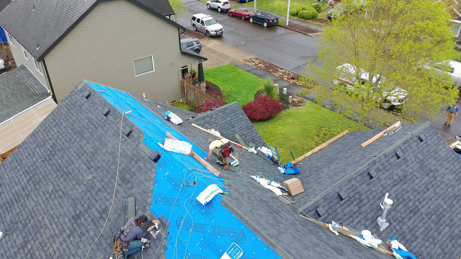 Aerial view of an Abiqua Roofing crew installing underlayment and new shingles on a two-story home
